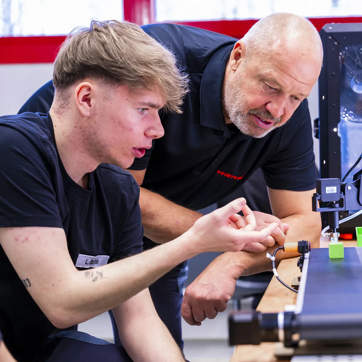 Apprentice with employee on mini robot